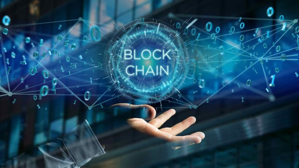 The words “block chain” and blue binary language hover above an open hand.
