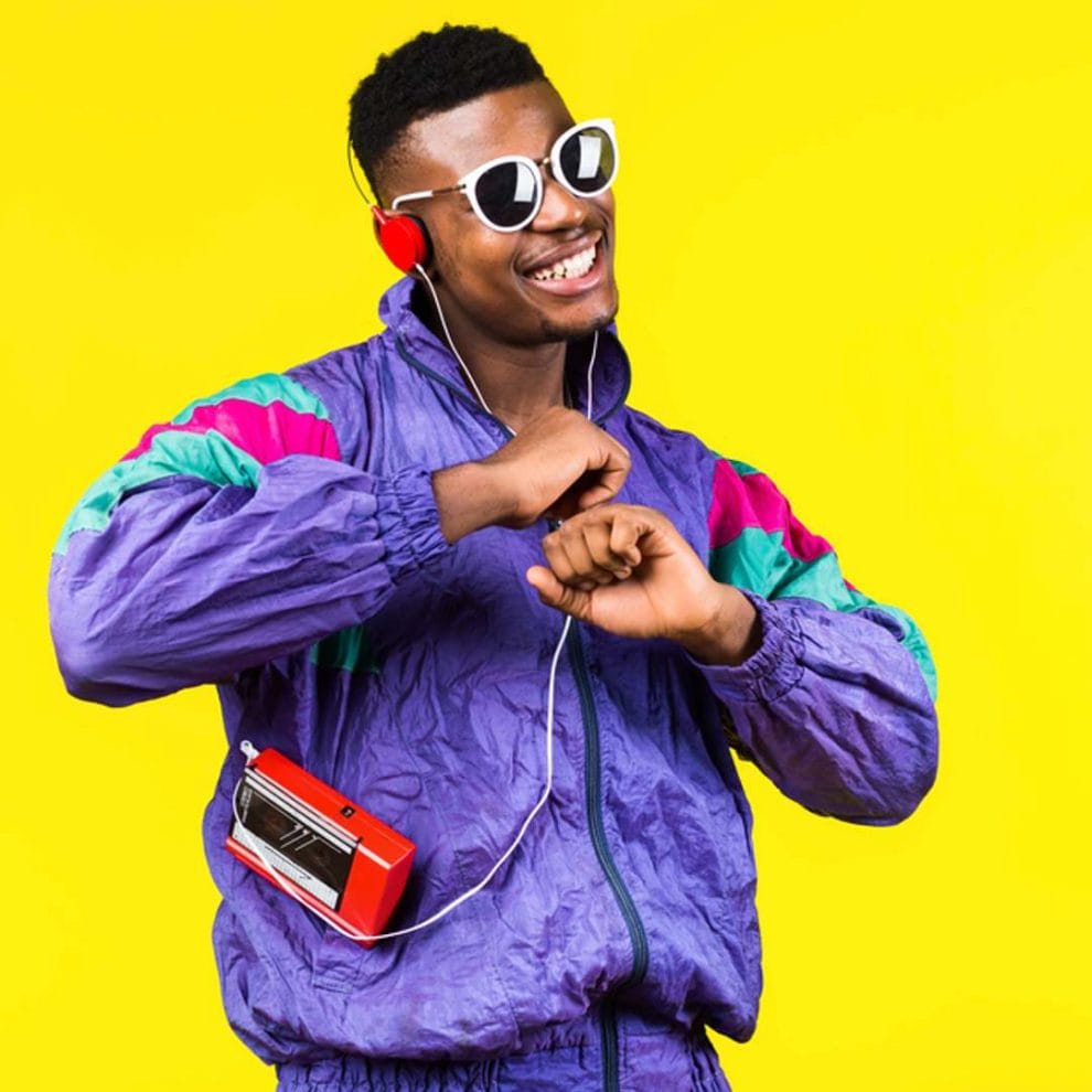 A man dressed in 80s-style tracksuit with a walkman on a yellow background.