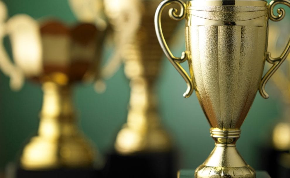 Golden trophies against a green background.