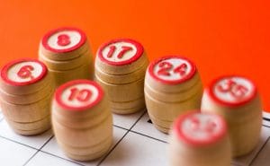 Bingo wooden barrels with numbers on a red surface.