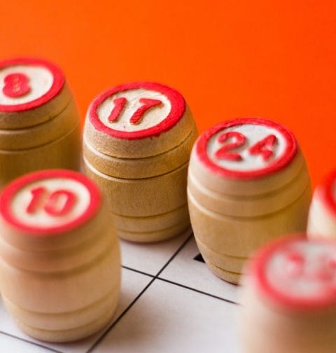 Bingo wooden barrels with numbers on a red surface.
