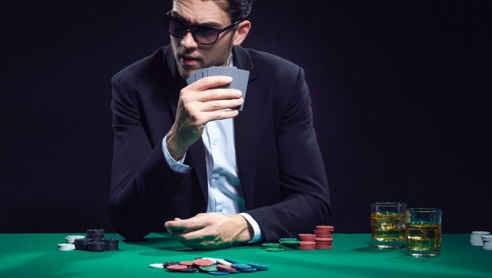 A man holds his poker cards close during a poker game.
