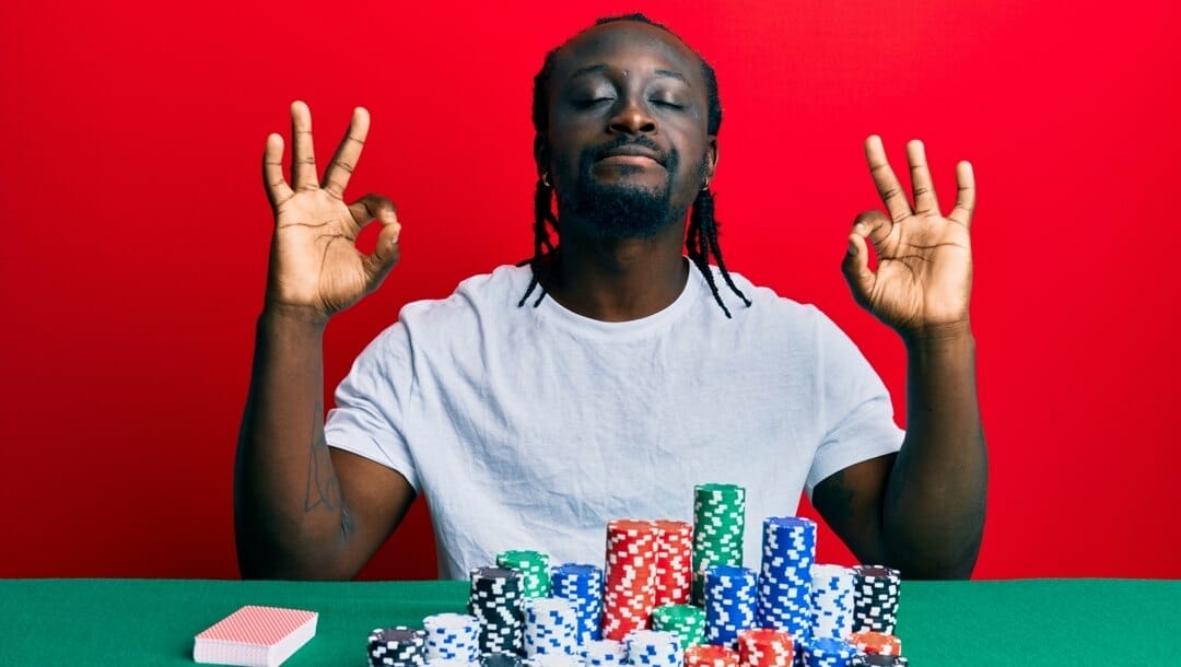 A man adopts a meditation pose before a game of poker.