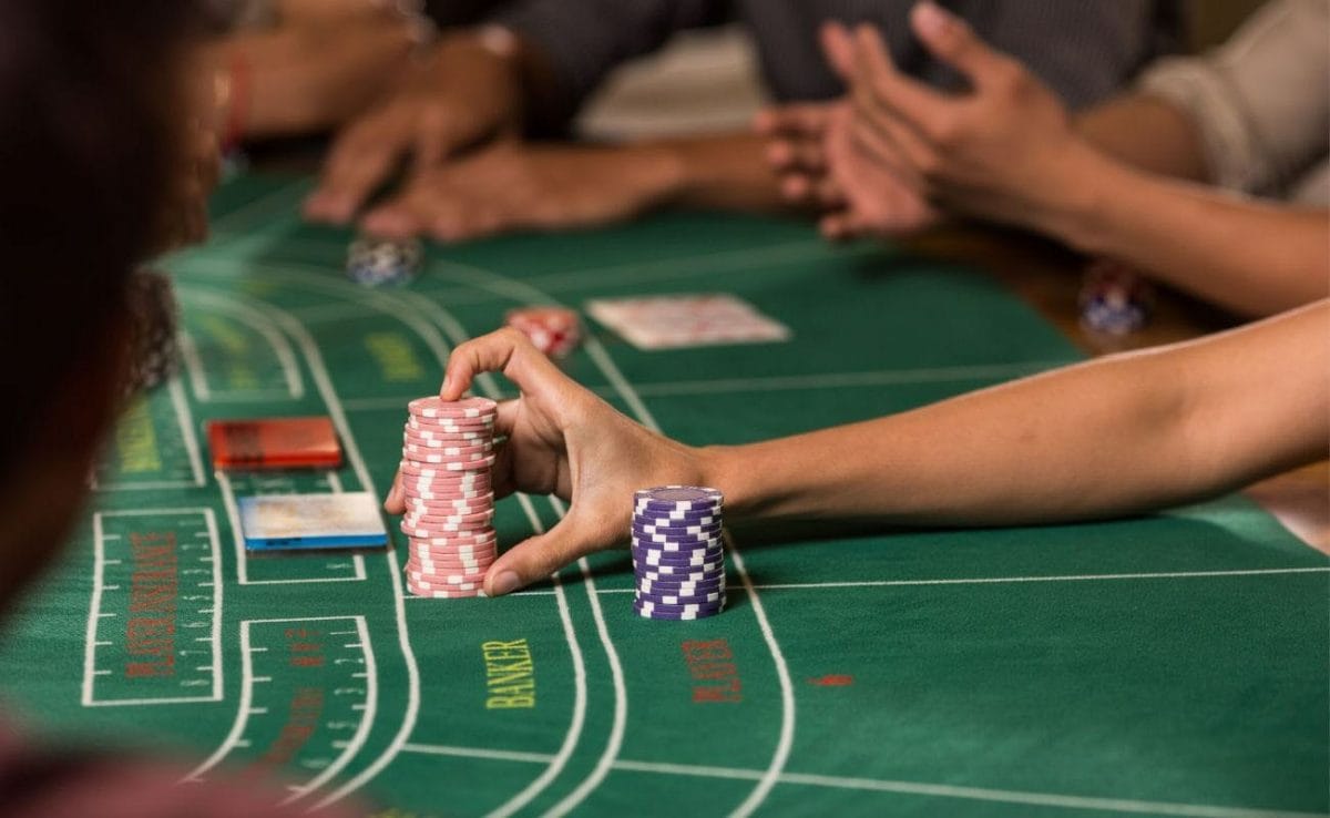 A woman holding a stack of tall chips at a casino table.
