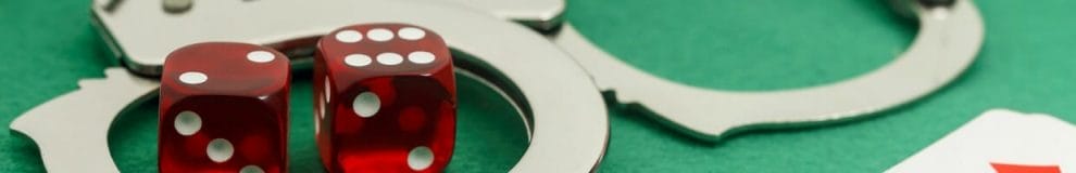 A pair of dice sitting inside a pair of handcuffs on a gambling table.