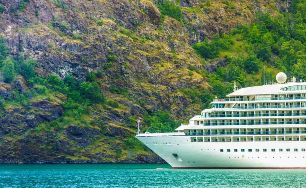 A cruise liner sailing past a mountain. 