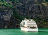 A cruise liner moored in front of a mountain.