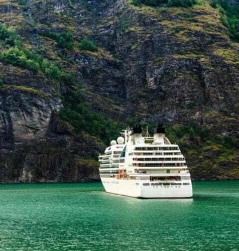 A cruise liner moored in front of a mountain.