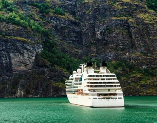 A cruise liner moored in front of a mountain.