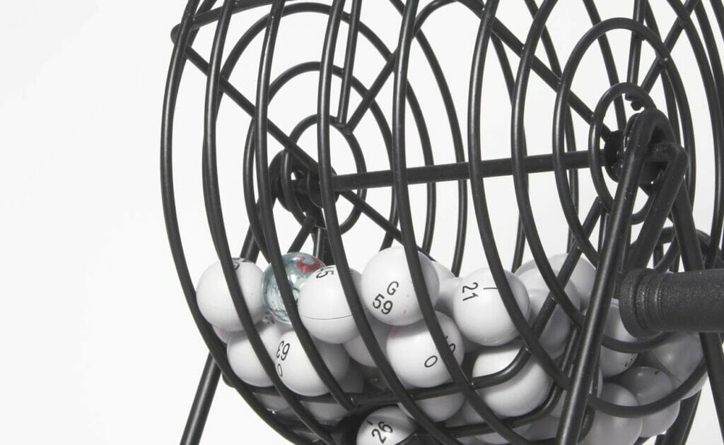 A close-up of a bingo cage filled with white bingo balls.
