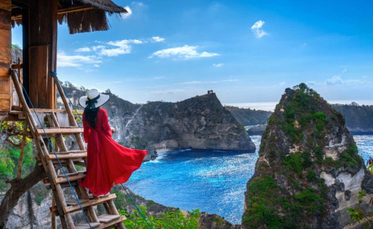 A woman in a red dress stares out over the sea in Bali. 