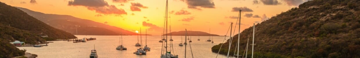 Sail boats in a harbor at sunset.
