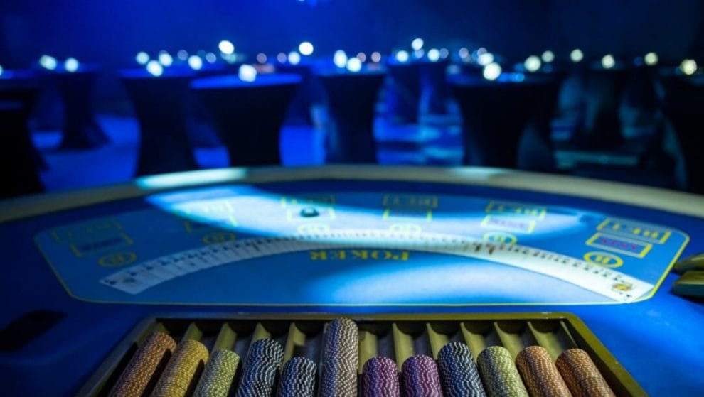 Digital rendering of an online poker table with rolls of chips in the foreground.