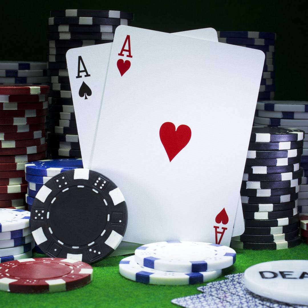 A close-up of two aces leaning against stacks of poker chips.