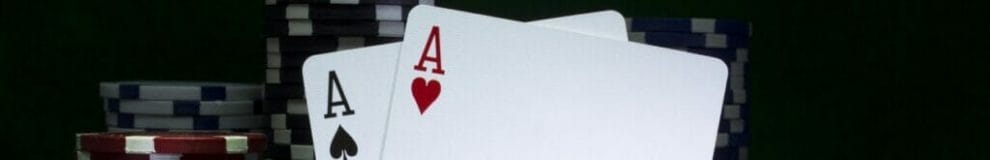 A close-up of two aces leaning against stacks of poker chips.