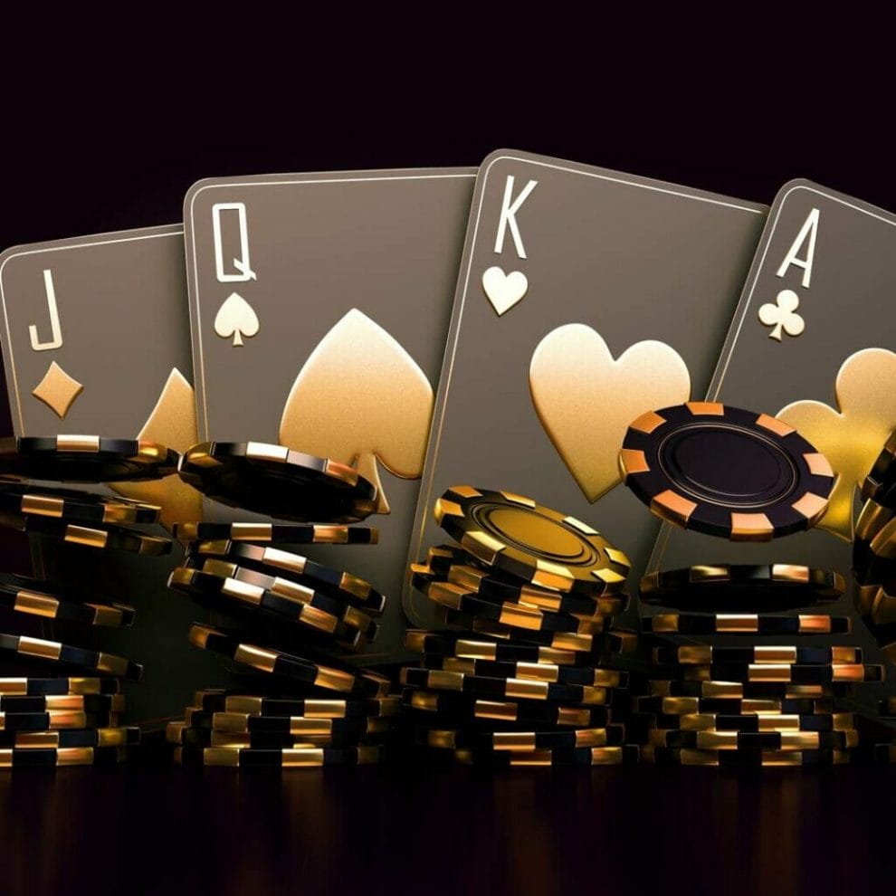 Four black and gold playing cards sit behind stacks of black and gold poker chips.