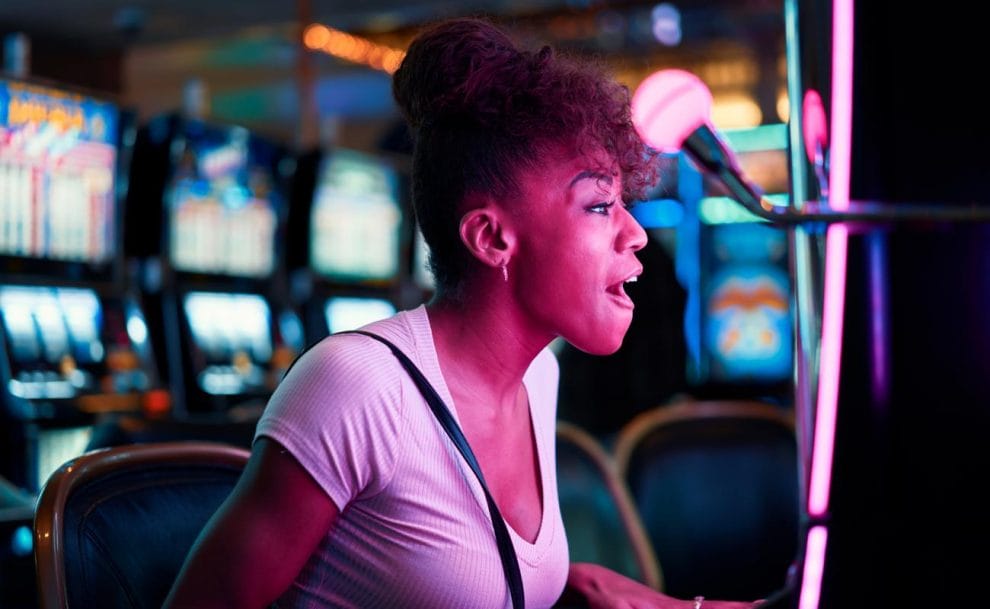 A person with an excited expression leans closer to a slot machine screen.