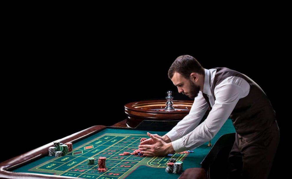 Roulette dealer piling up casino chips on a roulette table.