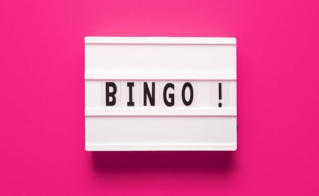White tiles with black letters on them form the word “BINGO!” against a bright pink background.