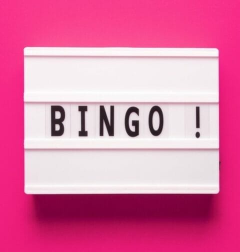 White tiles with black letters on them form the word “BINGO!” against a bright pink background.