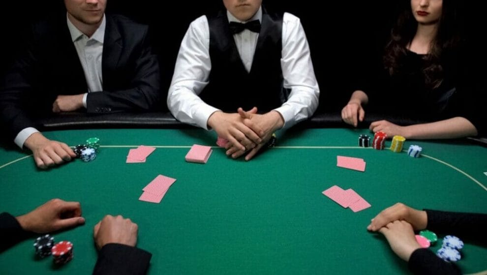 Poker players sitting around a poker table with their cards face-down.