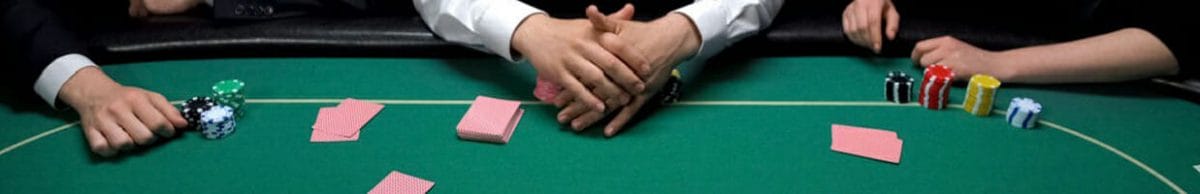 Poker players sitting around a poker table with their cards face-down.