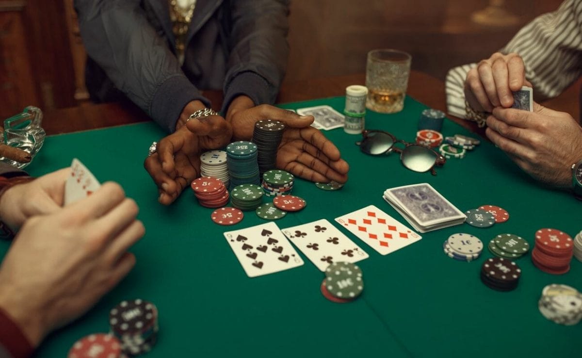 A man pushes his chips into the middle of the table and goes all-in in a casual cash poker game with friends.