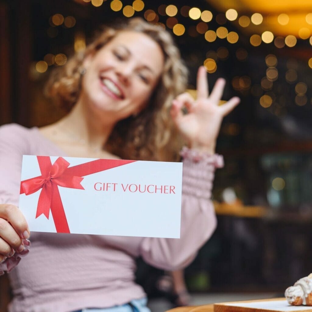 A smiling person holds up a gift voucher.