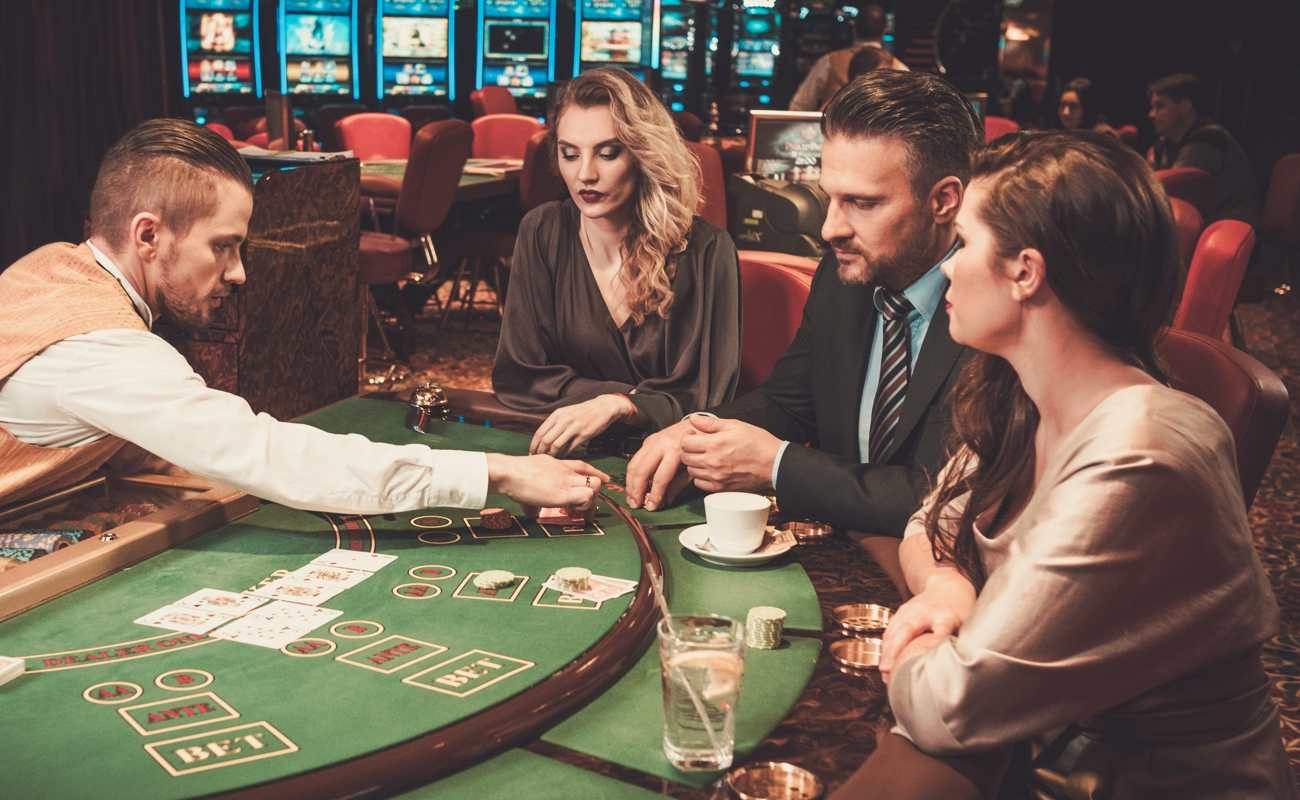 A dealer interacting with gamblers and dealing cards at a casino game table.