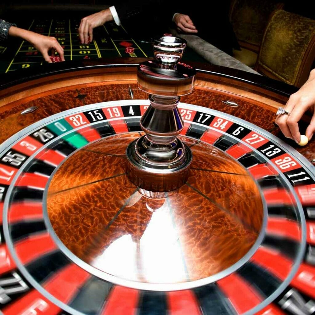 A close-up of a roulette wheel with the dealer about to drop the roulette ball into play.