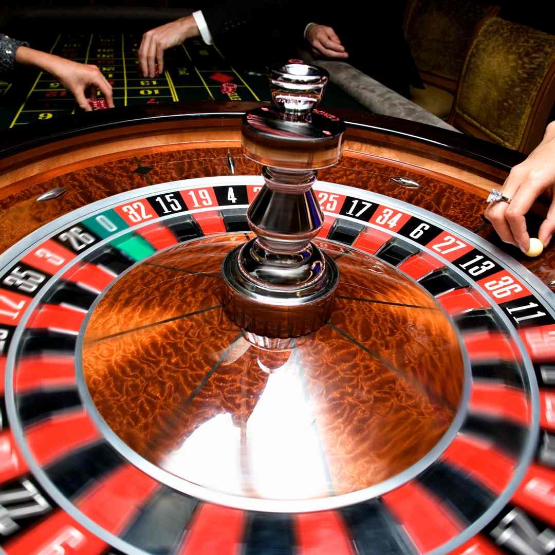 A close-up of a roulette wheel with the dealer about to drop the roulette ball into play.