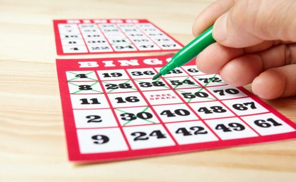 A hand marks a bingo card with a green marker.