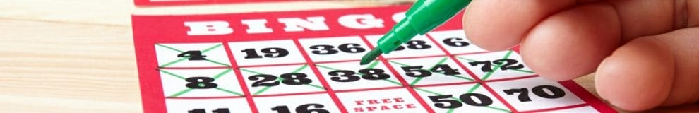 A hand marks a bingo card with a green marker.
