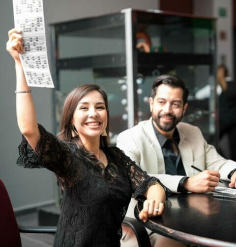 A happy woman holding up a winning bingo card.