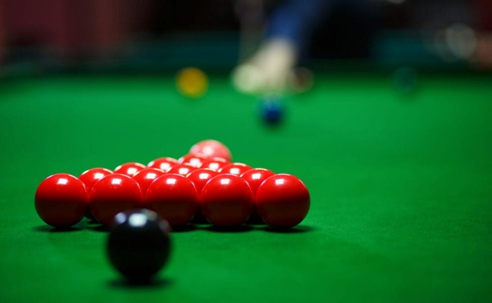 Snooker balls on a table with a player at the far end.