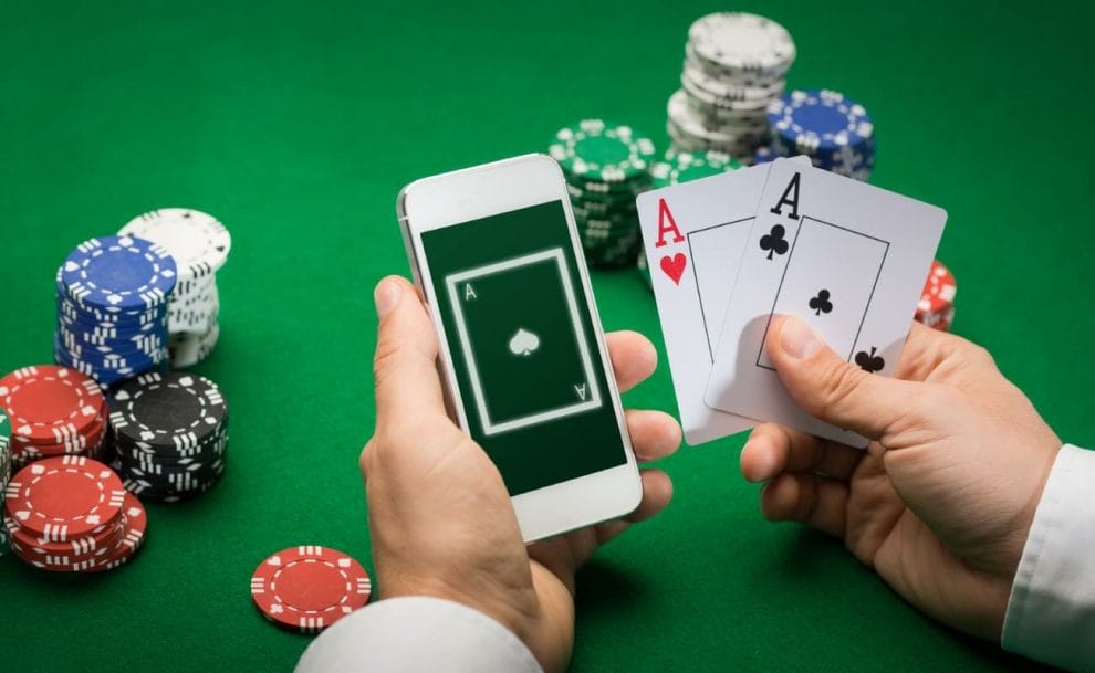 A man holding playing cards and a smartphone.