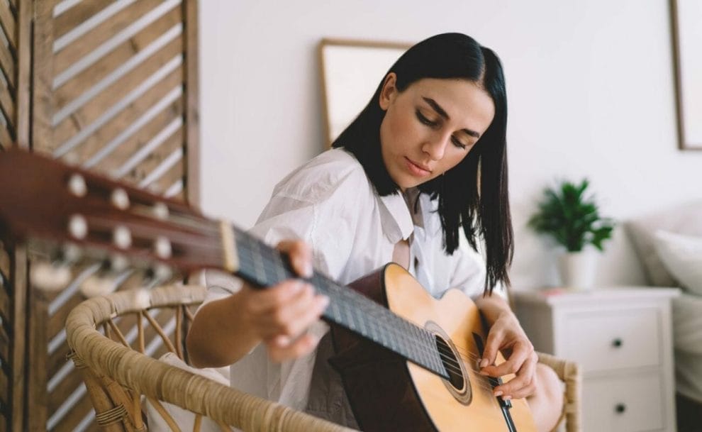 A woman playing guitar in her bedroom.