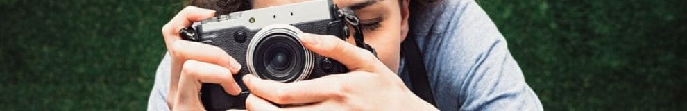 A woman looking through the viewfinder of a camera.