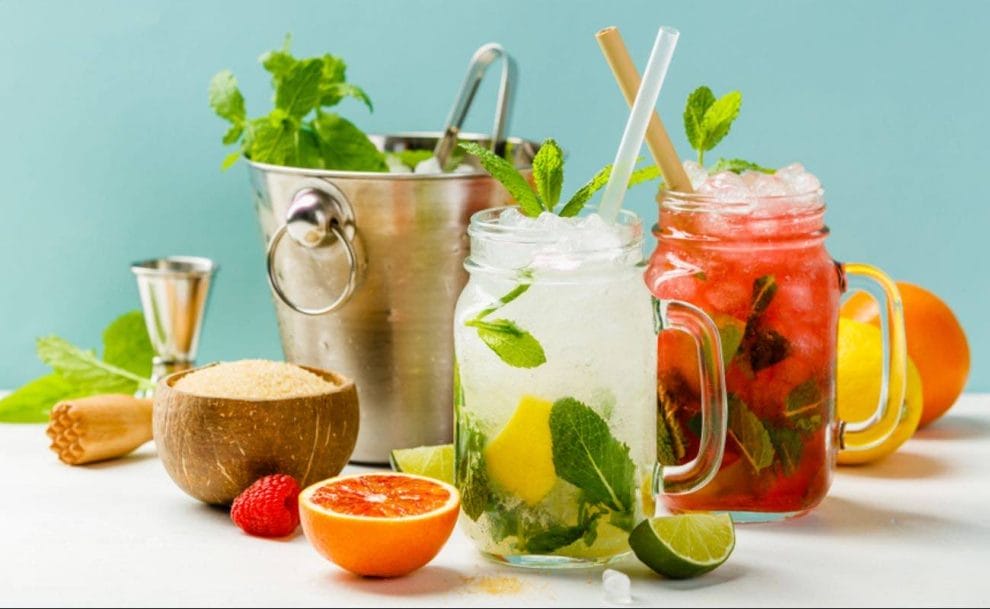 Colorful, non-alcoholic cocktails surrounded by fruits and vegetables.