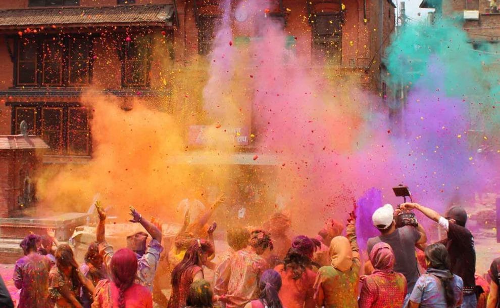 Holi celebration in Nepal, a crowd dancing with colored powder in the air.