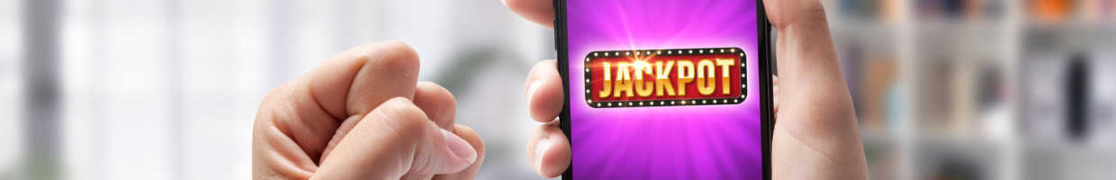 A man holding a phone with the word “Jackpot” on the screen.