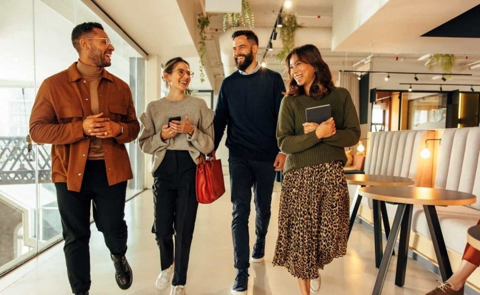 A diverse group of friends walks through a modern office space.