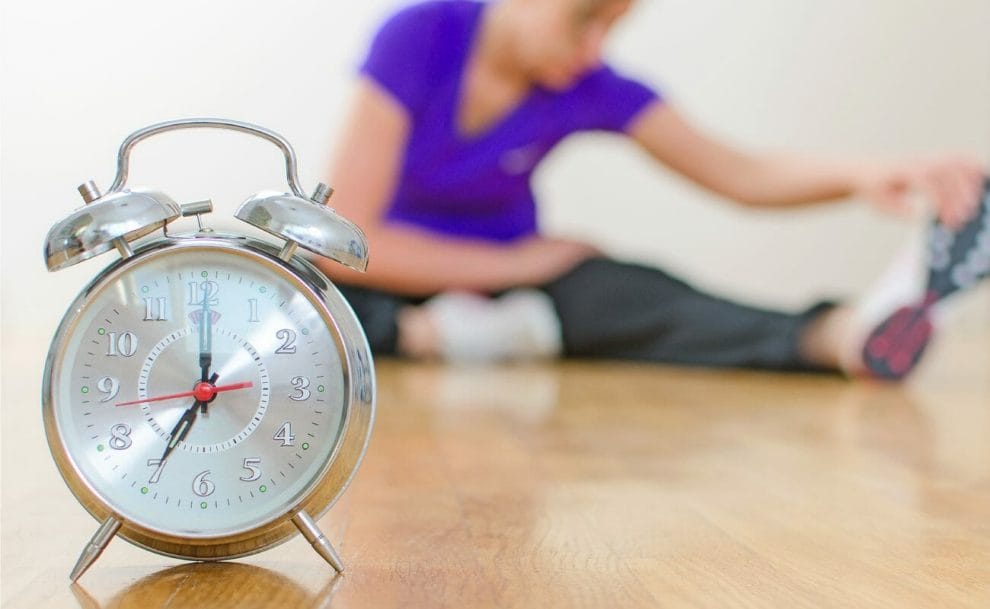 A woman exercising on the floor with a clock in the foreground.