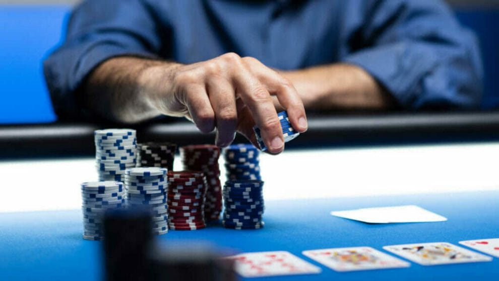 A person places chips down on the poker table.