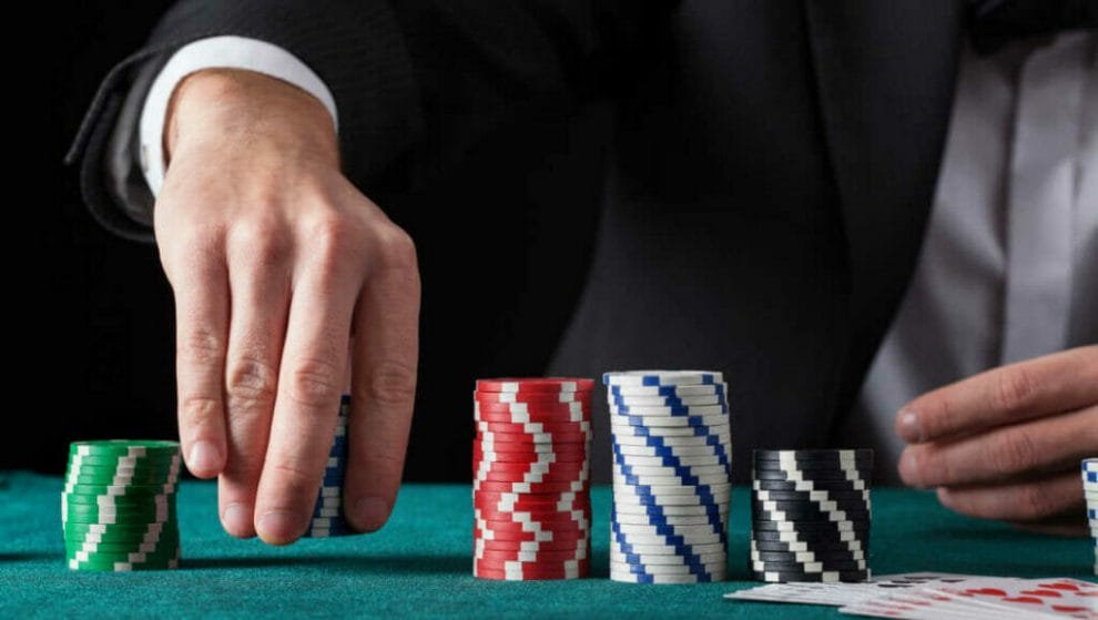 A person picks up a stack of chips on a poker table.