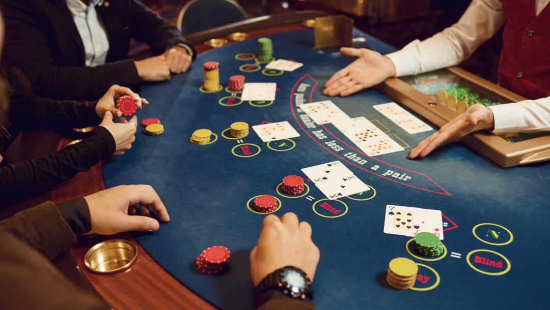 A croupier reveals the community cards to players at a poker table.