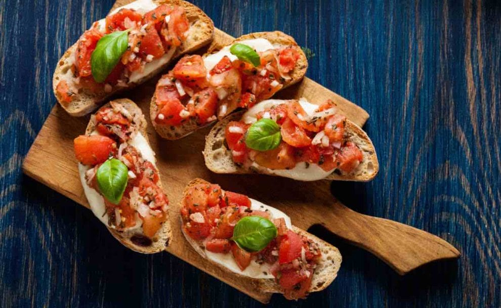 A wooden board with bruschetta on top of it. 