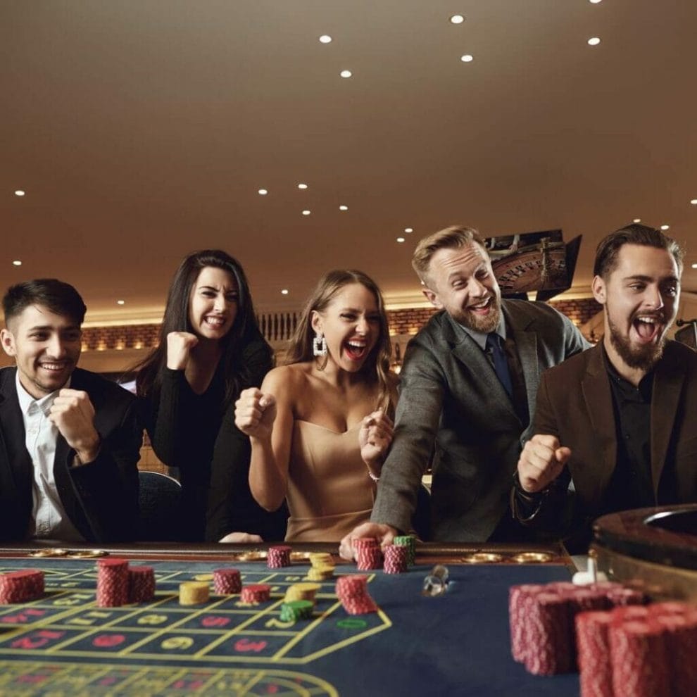 A group of people cheering at a casino game table.
