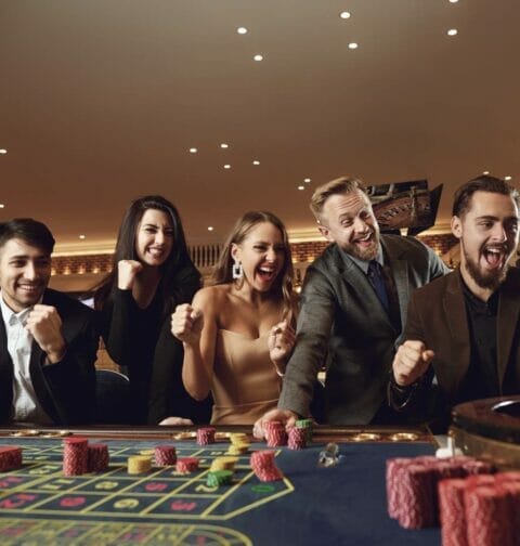 A group of people cheering at a casino game table.