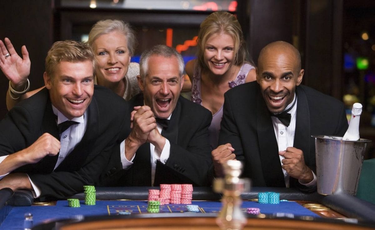 A group of well-dressed friends cheers while playing roulette.